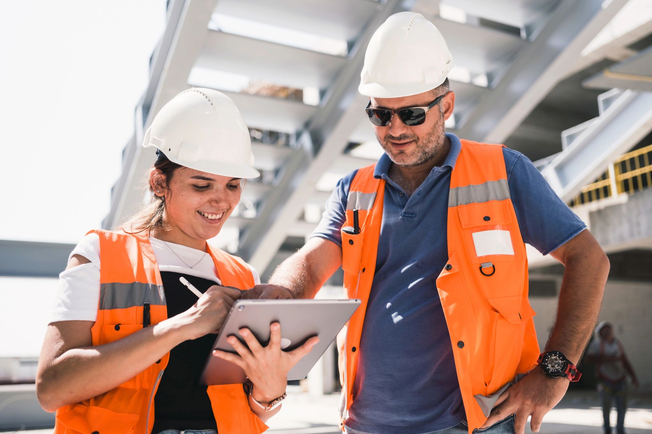 Engineers using a tablet at a worksite to verify project requirements