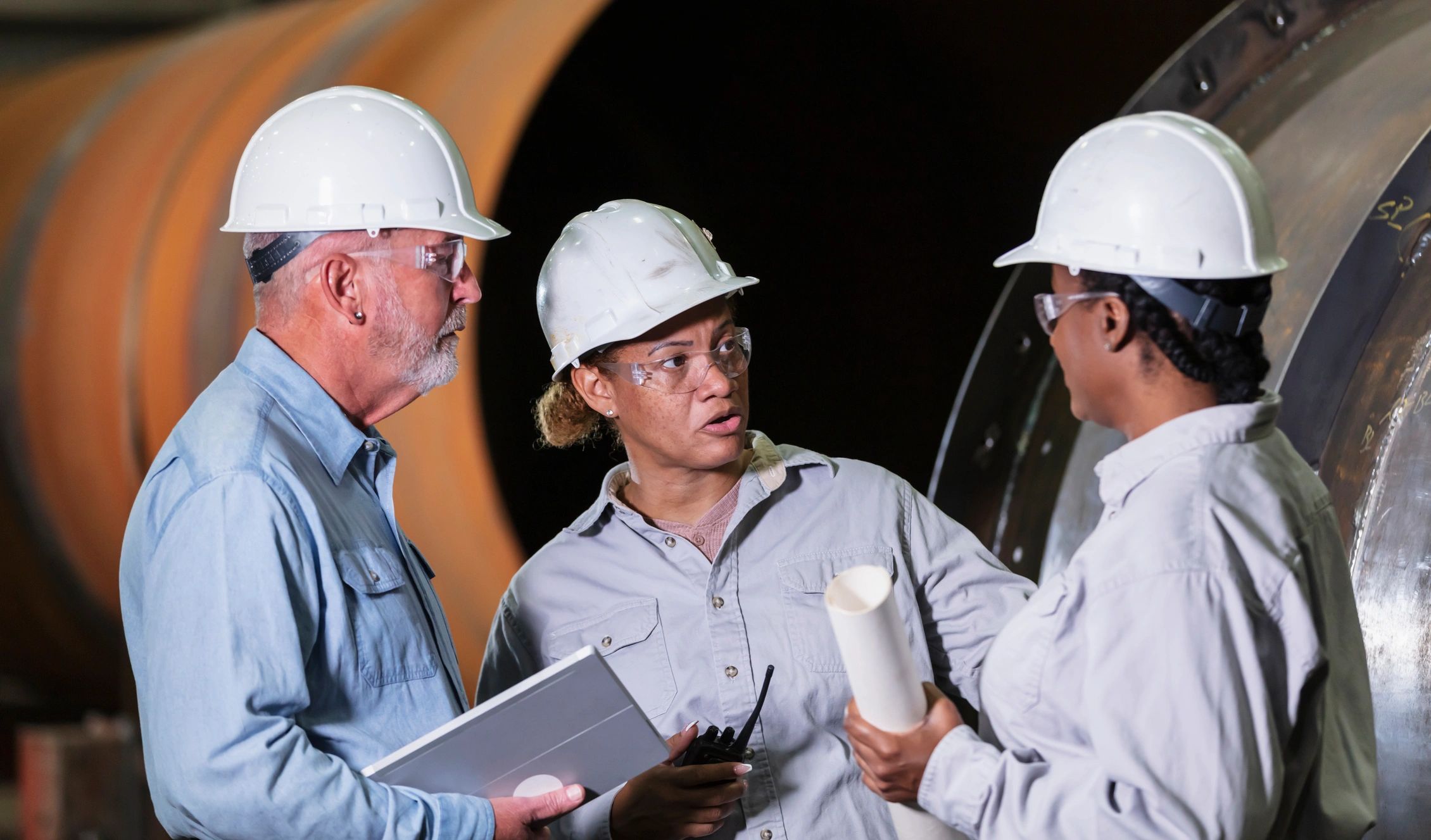 Industrial team meeting on a factory floor discussing safety and operations