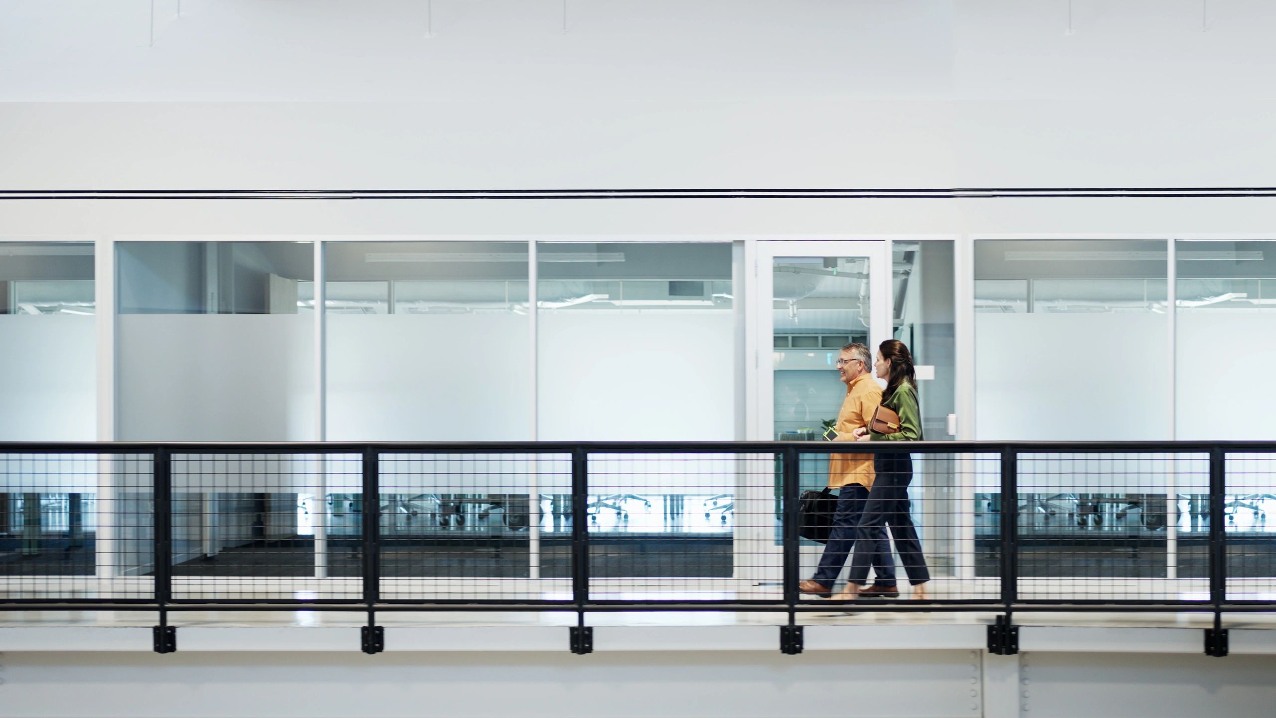 Two professionals walking and discussing compliance planning at a conference venue