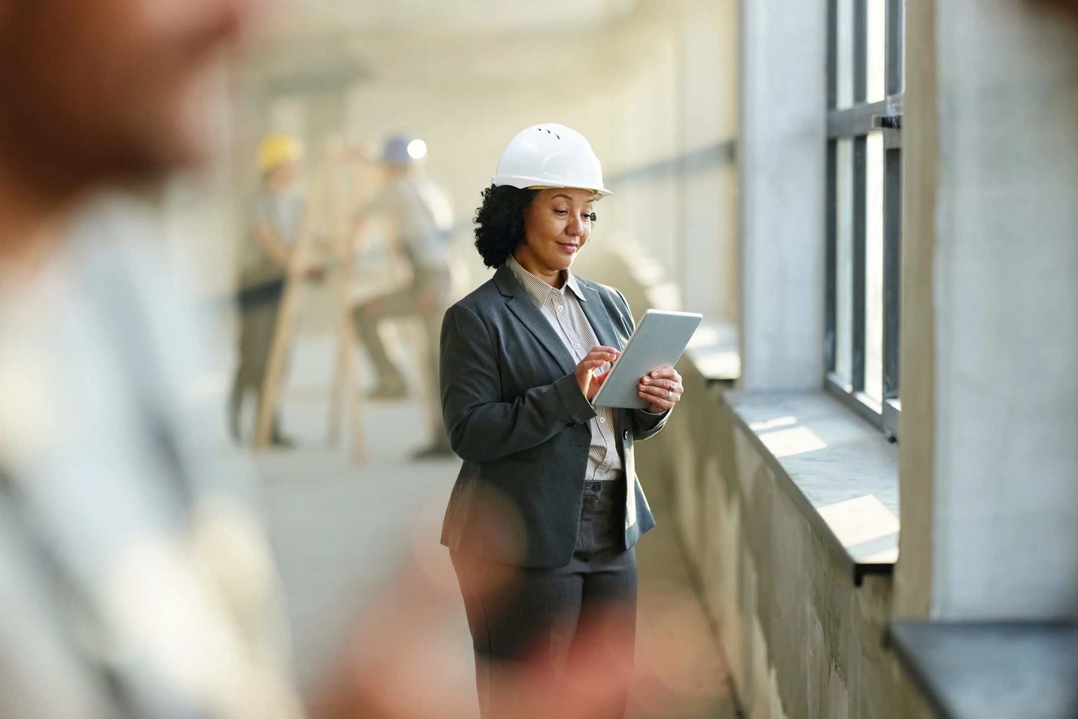 Professional using a tablet at a worksite, representing a client stakeholder